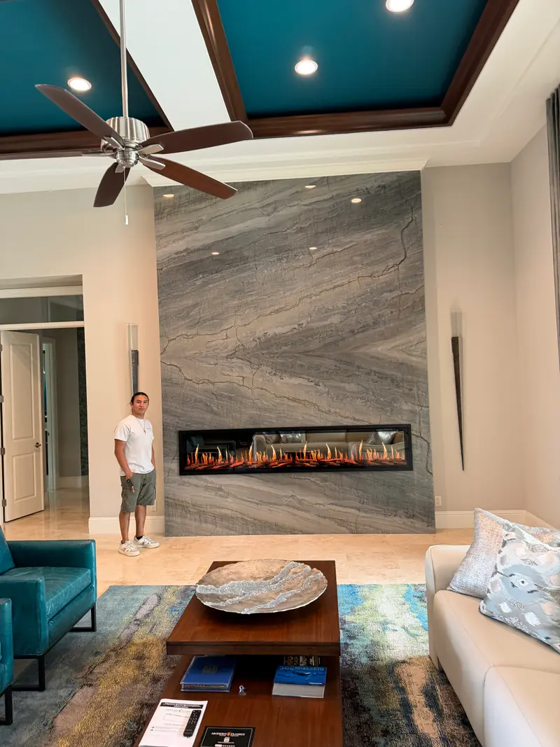 Floor-to-ceiling granite fireplace wall with a team member standing beside it for scale