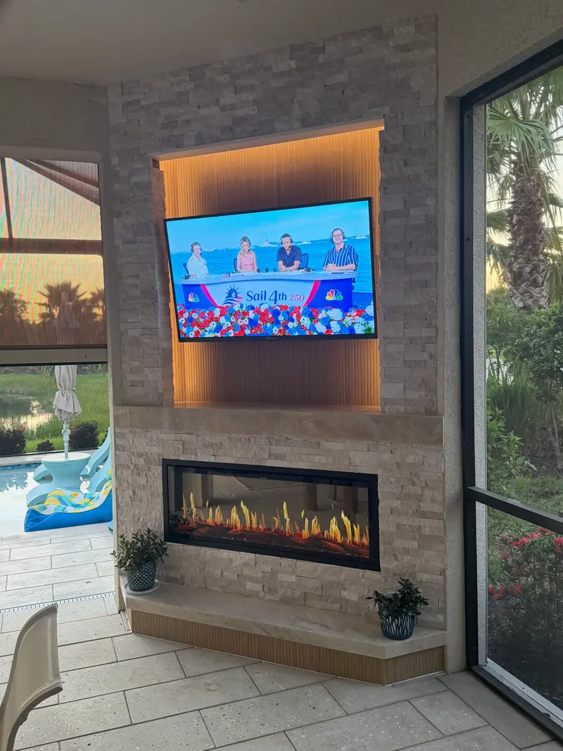Stacked-stone fireplace wall with a lit wood niche on a screened lanai