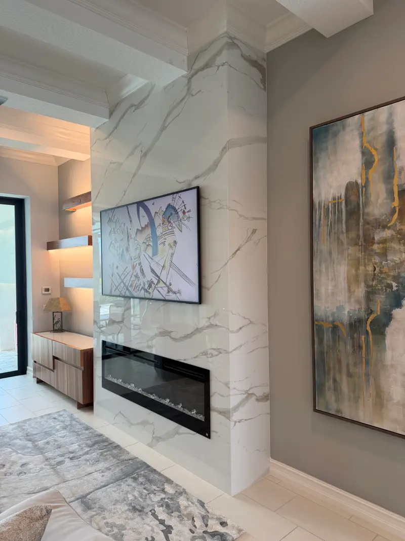 Floor-to-ceiling marble-look feature wall with a linear electric fireplace and art-framed TV