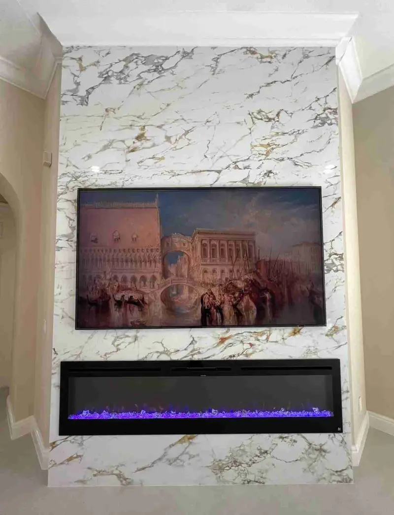 Gold-veined marble slab feature wall with an art-framed TV and a wide linear electric fireplace