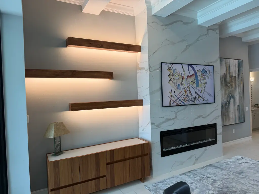 Marble-look feature wall with lit walnut floating shelves and a linear fireplace