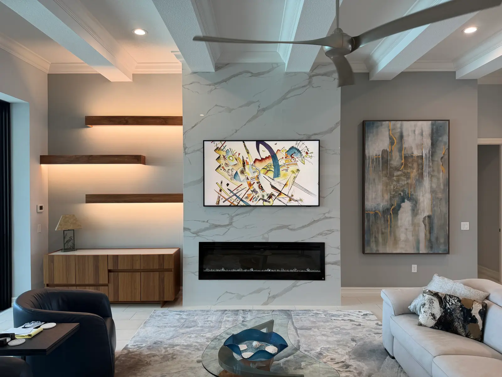 Marble-look feature wall with lit walnut floating shelves and a linear electric fireplace