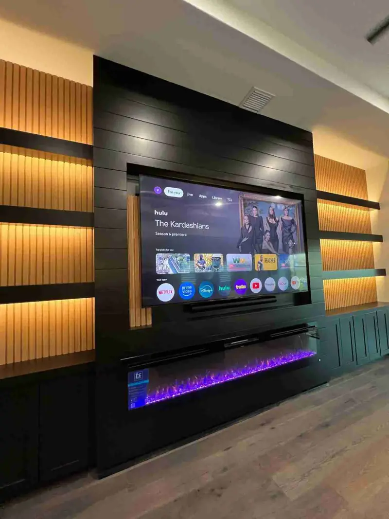 Black media wall with premium backlit slatted wall panels and a long linear electric fireplace