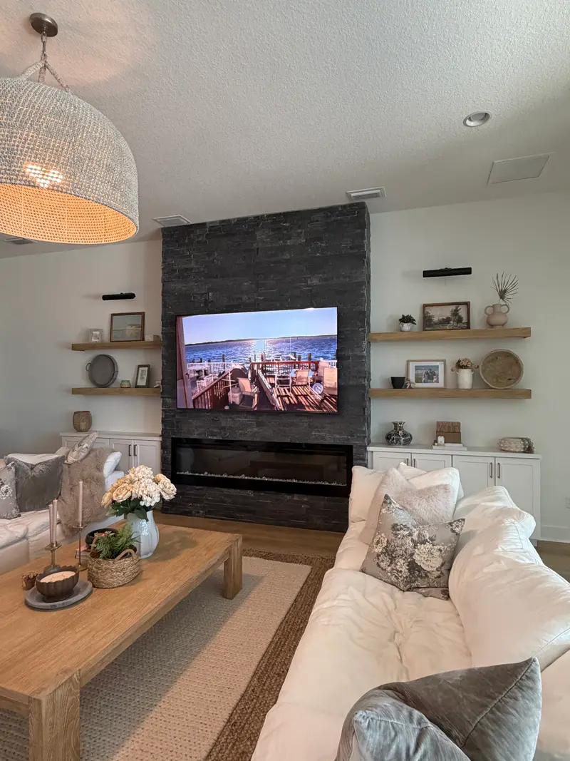 Dark stacked-stone fireplace wall flanked by floating shelves