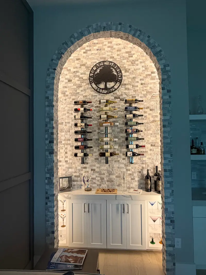 Stone archway wine nook with lit bottle racks