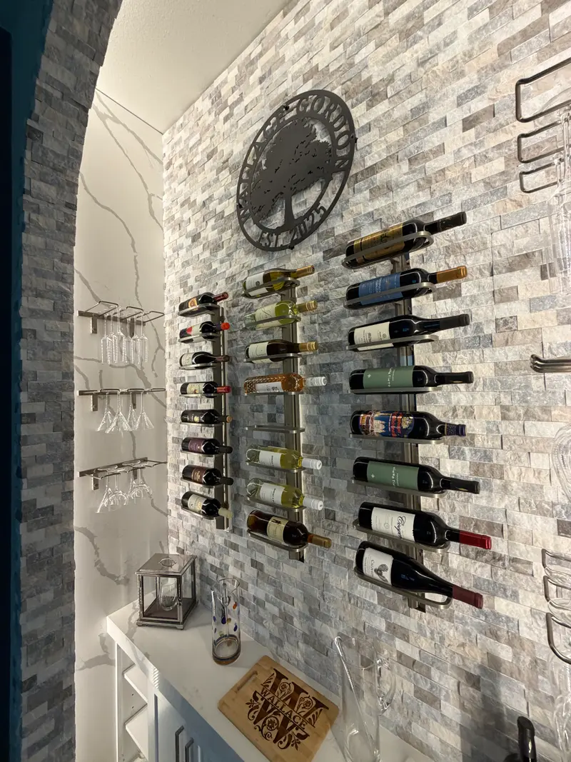 Close view of wall-mounted wine racks and glass holders on a stone mosaic wall